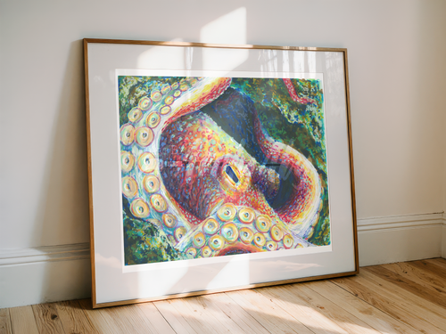 A framed art print of a colorful octopus resting on a light wood floor against a white wall, with natural sunlight casting shadows across the frame.